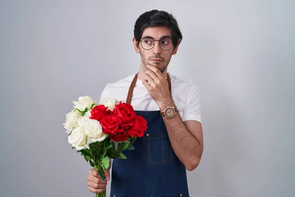 Joven Hombre Hispano Sosteniendo Ramo Rosas Blancas Rojas Pensando Preocupado —  Fotos de Stock