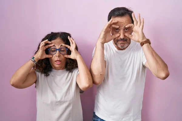 Középkorú Spanyol Házaspár Együtt Rózsaszín Háttér Próbál Nyitott Szemmel Ujjakkal — Stock Fotó