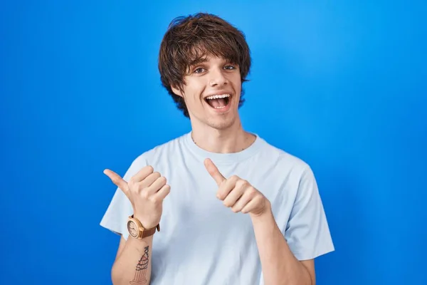 Hispanic Young Man Standing Blue Background Pointing Back Hand Thumbs — Stockfoto