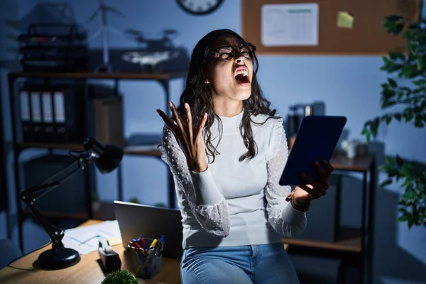 オフィスで働く夜のタッチパッドを使っている若いブラジル人女性は狂った叫び 積極的な表情と腕を上げて叫びました フラストレーションコンセプト — ストック写真