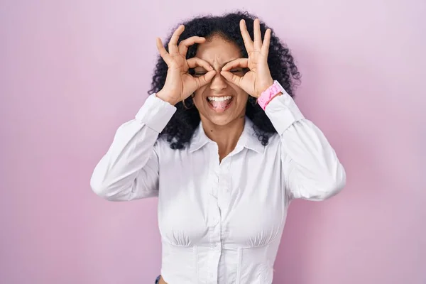 Hispanic Woman Curly Hair Standing Pink Background Doing Gesture Binoculars — Foto de Stock