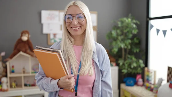 Junge Blonde Kindergärtnerin Lächelt Selbstbewusst Und Hält Bücher Kindergarten — Stockfoto