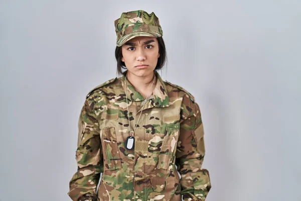 Young south asian woman wearing camouflage army uniform skeptic and nervous, frowning upset because of problem. negative person.