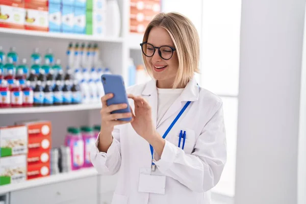 Young Blonde Woman Pharmacist Using Smartphone Working Pharmacy — 图库照片