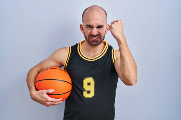 Young Bald Man Beard Wearing Basketball Uniform Holding Ball Angry — Stock Photo, Image