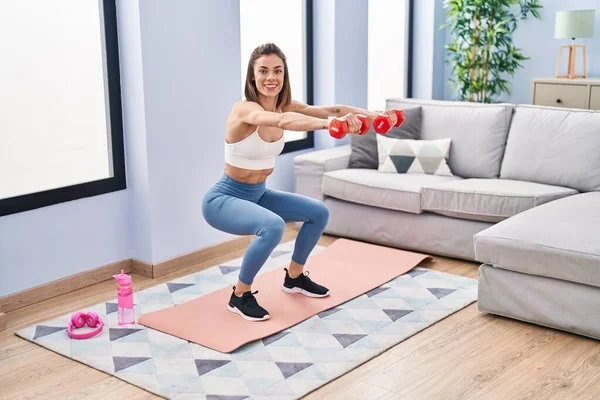 Young Beautiful Hispanic Woman Training Leg Exercise Using Dumbbells Home — Stockfoto