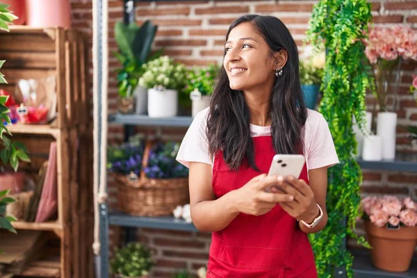 Joven Hermosa Florista Hispana Sonriendo Confiada Usando Teléfono Inteligente Tienda —  Fotos de Stock