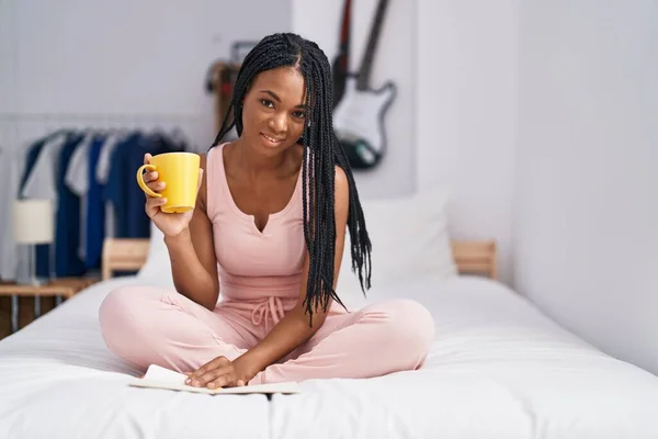 アフリカ系アメリカ人女性が寝室でコーヒーを飲む紙を読む — ストック写真