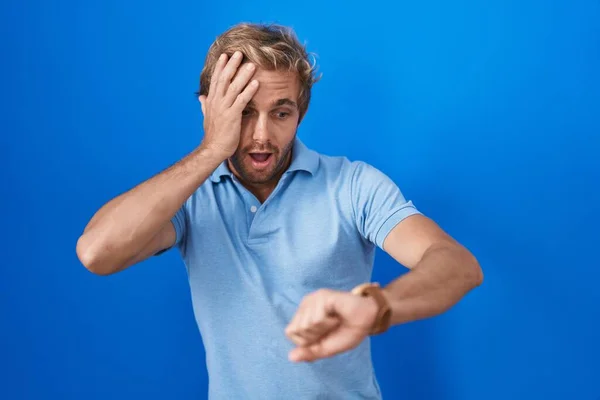 Kafkasyalı Bir Adam Mavi Arka Planda Dikiliyor Saate Bakıyor Endişeli — Stok fotoğraf