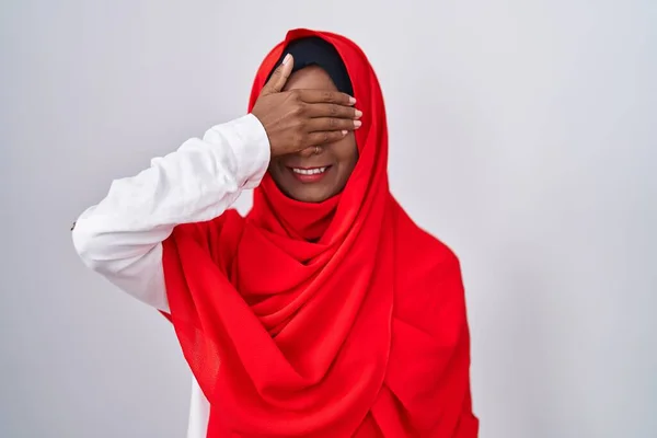 伝統的なイスラム教のヒジャーブスカーフを身に着けている若いアラブの女性は笑顔と驚きのために目をカバー顔に手で笑っています 視覚障害の概念 — ストック写真