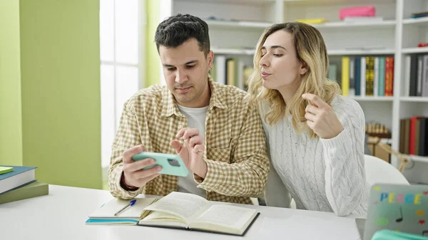 Erkek Kadın Öğrenciler Kütüphane Üniversitesinde Akıllı Telefon Kullanarak Birlikte Okuyorlar — Stok fotoğraf