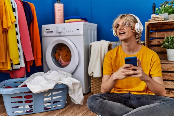 Νεαρός Ξανθός Άντρας Ακούει Μουσική Περιμένοντας Πλυντήριο Στο Πλυσταριό — Φωτογραφία Αρχείου