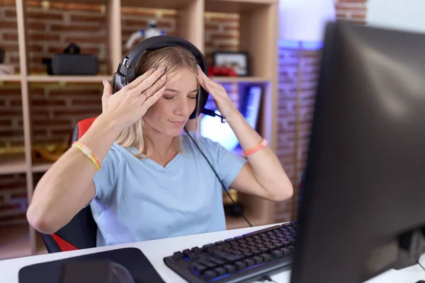 ストレスのために頭の上に手でヘッドフォンを身に着けているビデオゲームをプレイ若い白人女性 片頭痛 — ストック写真