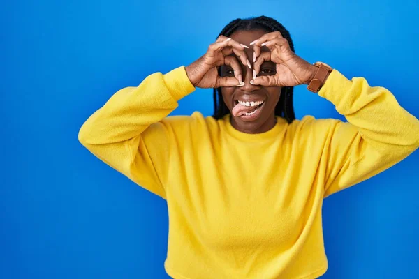 Beautiful Black Woman Standing Blue Background Doing Gesture Binoculars Sticking — Foto Stock