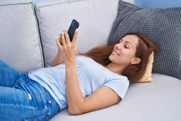 Νεαρή Γυναίκα Χρησιμοποιώντας Smartphone Ξαπλωμένη Στον Καναπέ Στο Σπίτι — Φωτογραφία Αρχείου