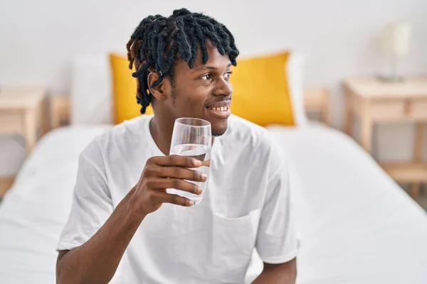 アフリカ系アメリカ人男性飲料水のガラスベッドルームでベッドに座って — ストック写真
