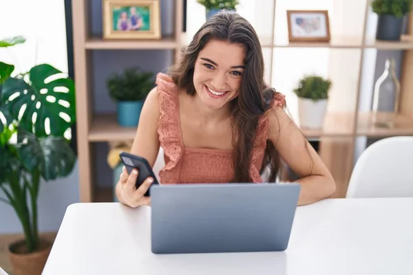 在家里用笔记本电脑和智能手机的年轻女人 — 图库照片