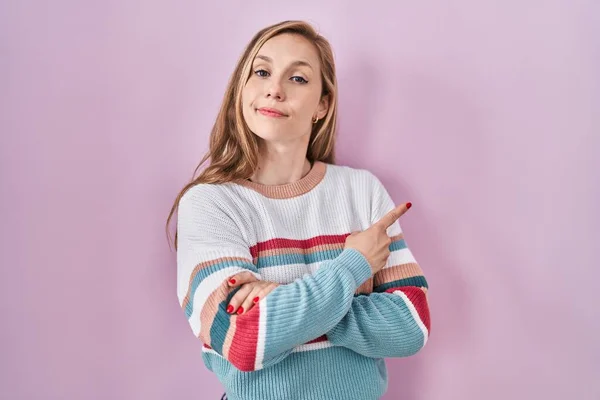 Young Blonde Woman Standing Pink Background Pointing Hand Finger Side — Stockfoto