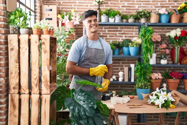 Young hispanic man florist using difusser working at flower shop
