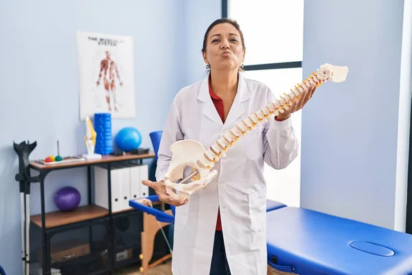 Medelålders Latinamerikanska Kvinna Med Anatomisk Modell Ryggraden Tittar Kameran Blåser — Stockfoto