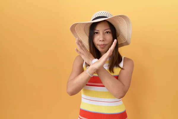 中年妇女戴着夏帽顶着黄色背景的排斥表情 交叉着双臂做着消极的手势 怒气冲冲的脸 — 图库照片