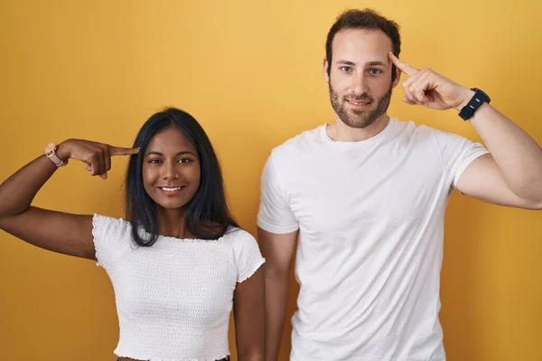 Interracial Couple Standing Yellow Background Smiling Pointing Head One Finger — Stock Photo, Image