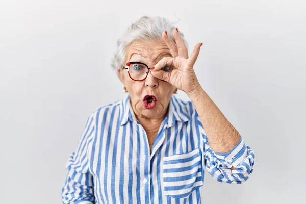 白发苍苍的老妇人站在白种人的背景上 摆出一副惊讶的样子 用手指看过去 不信的表情 — 图库照片