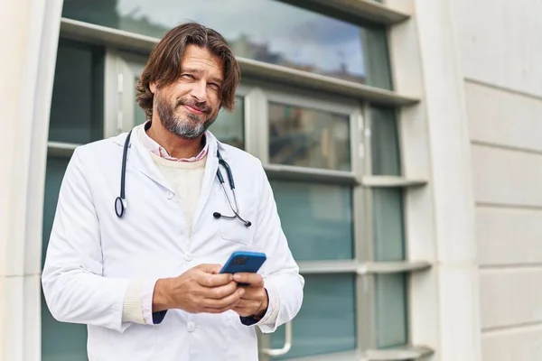 Médico Hombre Mediana Edad Sonriendo Confiado Usando Teléfono Inteligente Hospital —  Fotos de Stock