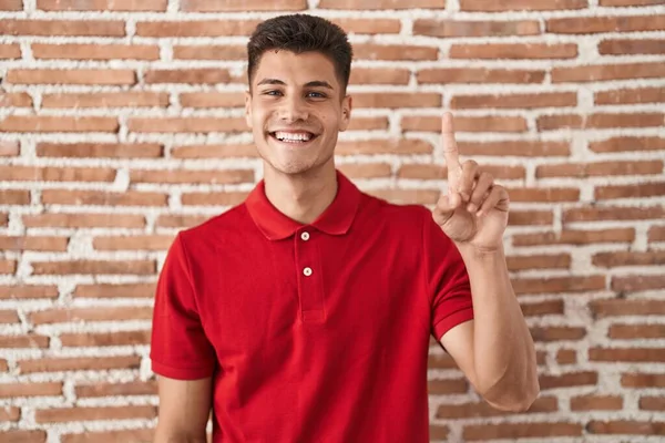 Junger Hispanischer Mann Steht Über Ziegelmauer Und Zeigt Mit Finger — Stockfoto