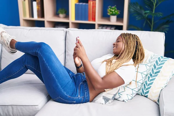 Mujer Afroamericana Usando Teléfono Inteligente Tumbado Sofá Casa — Foto de Stock