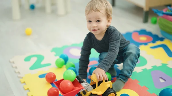 Sevimli Sarışın Çocuk Anaokulunda Yerde Oturmuş Traktör Oyuncağı Oynuyor — Stok fotoğraf