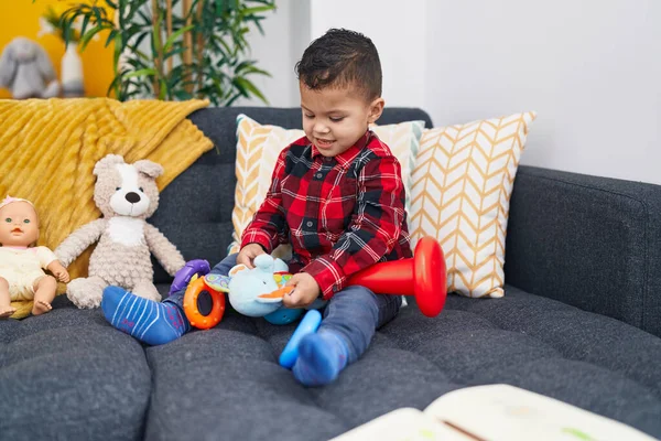 Uroczy Latynoski Chłopiec Siedzący Kanapie Bawiący Się Domu Zabawką Dla — Zdjęcie stockowe