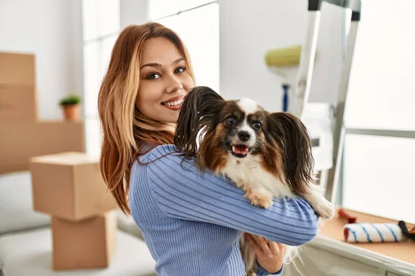 Young caucasian woman smiling confident hugging dog at new home