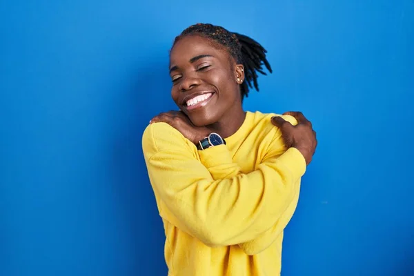 Beautiful Black Woman Standing Blue Background Hugging Oneself Happy Positive — Stock Photo, Image