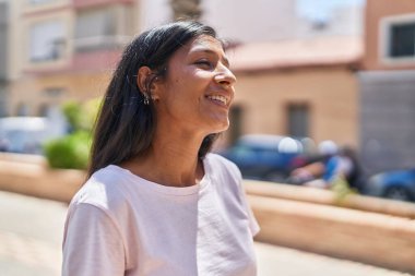 Young beautiful hispanic woman smiling confident looking to the side at street