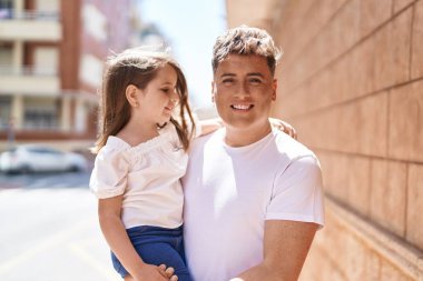 Baba ve kızı gülümsüyor, sokakta birbirlerine sarılıyorlar.
