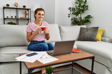 Kahve içen genç bir kadın evde çalışıyor.