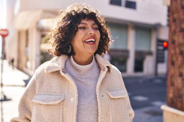 Young beautiful hispanic woman smiling confident looking to the side at street
