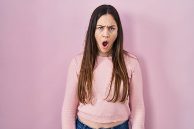 Pembe arka planda duran genç esmer kadın şok olmuş gibi, şüpheci ve alaycı görünüyor, ağzı açık kalınca şaşırıyor. 