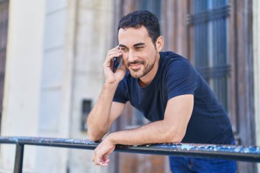 Genç İspanyol adam gülümsüyor. Kendine güveniyor. Sokakta akıllı telefondan konuşuyor.