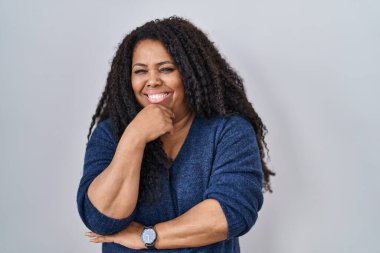 Ayrıca beyaz arka planda duran boyda İspanyol bir kadın kameraya kollarını kavuşturup gülümseyerek ve çenesini kaldırarak bakıyor. Olumlu düşünmek. 