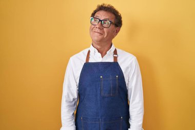 Orta yaşlı İspanyol bir adam profesyonel aşçı önlüğü giyiyor gülümsüyor, yan tarafa bakıyor ve düşünüyor.. 