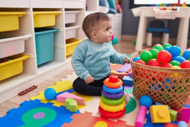 Anaokulunda yerde oturan sevimli İspanyol bebek.