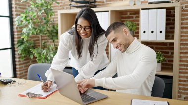 Man and woman business workers using laptop writing on document at office