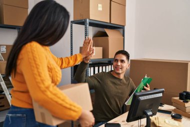 Man and woman ecommerce business workers high five with hands raised up at ecommerce office