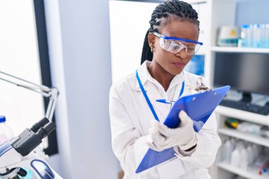African american woman scientist writing report working at laboratory