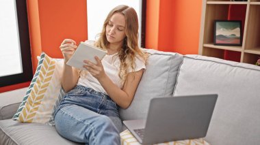 Evde dizüstü bilgisayar kullanan genç sarışın kadın.