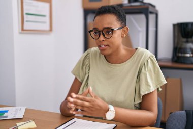African american woman business worker sitting on table speaking at office