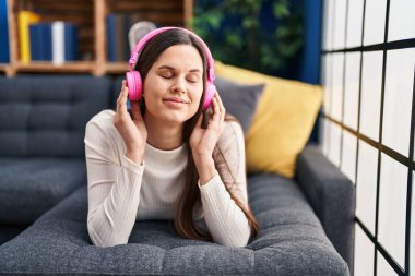 Evdeki kanepede uzanmış müzik dinleyen genç, güzel İspanyol kadın.