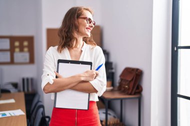 Genç, güzel, İspanyol bir iş kadını. Ofiste elinde bir panoyla gülümsüyor.